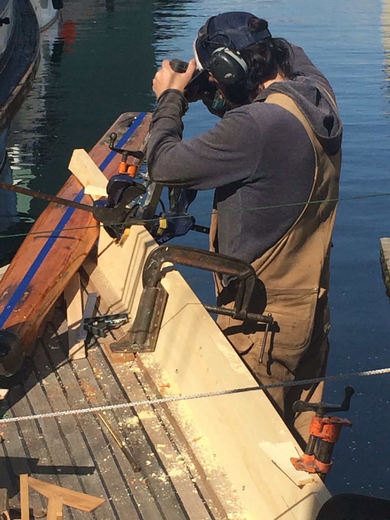 A diver in full gear prepares for underwater work on the classic 1946 Philip Rhodes-designed Merry Maiden, her hull gleaming white and cream in the bright sunlight.