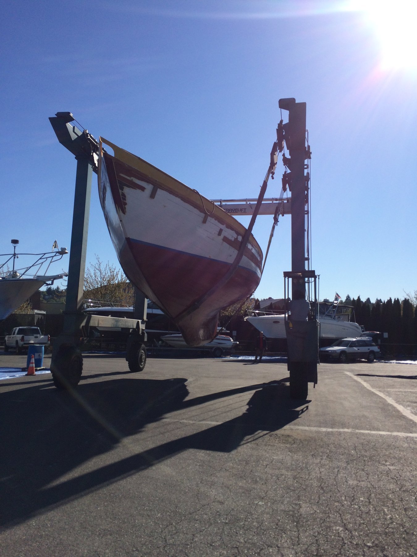 The classic 1946 Philip Rhodes-designed Merry Maiden displays her elegant burgundy hull and graceful lines while moored in the calm waters of Puget Sound, her traditional rigging silhouetted against a clear spring sky.
