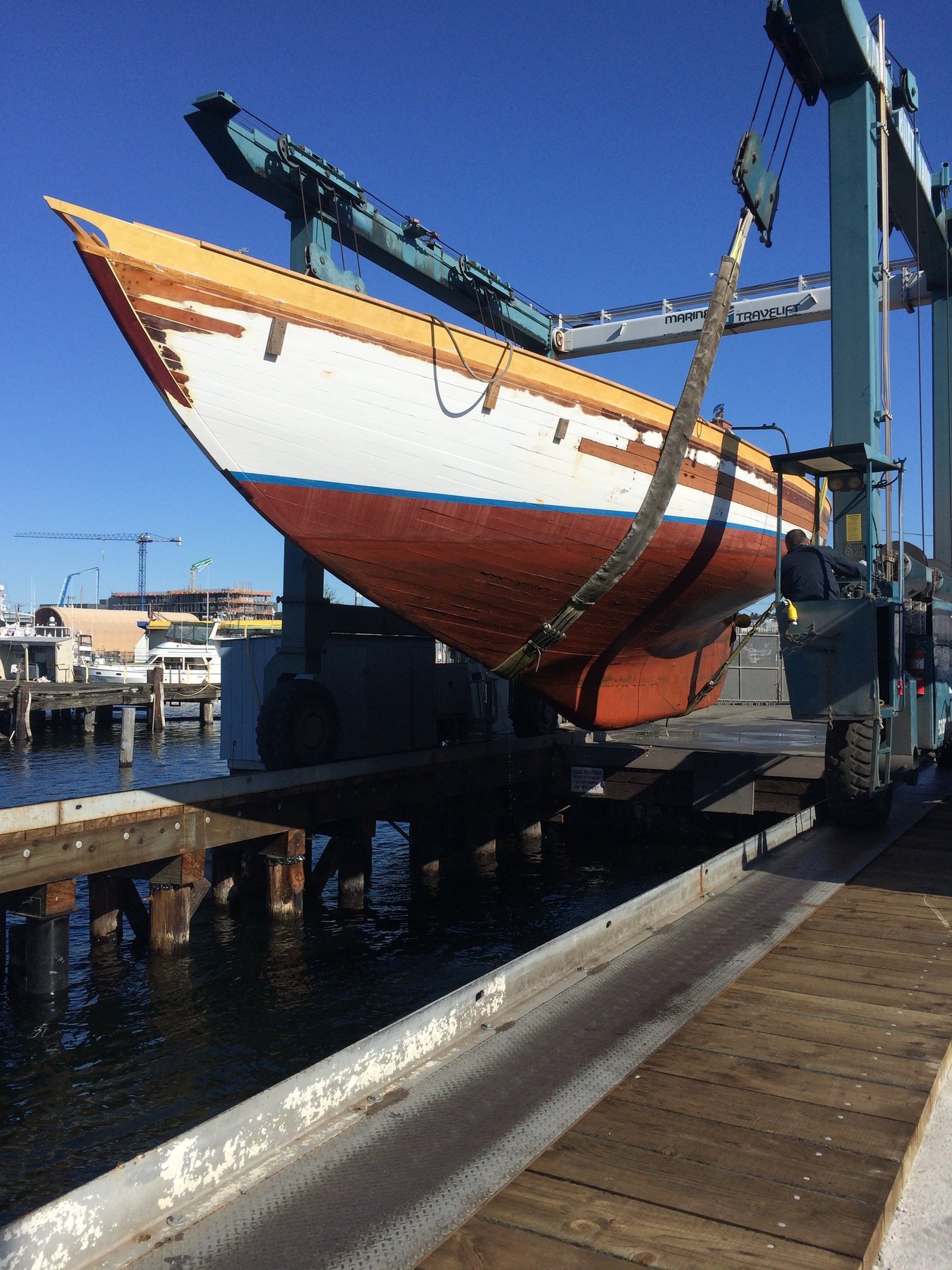 The classic 1946 Philip Rhodes-designed Merry Maiden displays her graceful lines and distinctive red hull under clear skies in Puget Sound, her elegant design exemplifying mid-century wooden yacht craftsmanship.