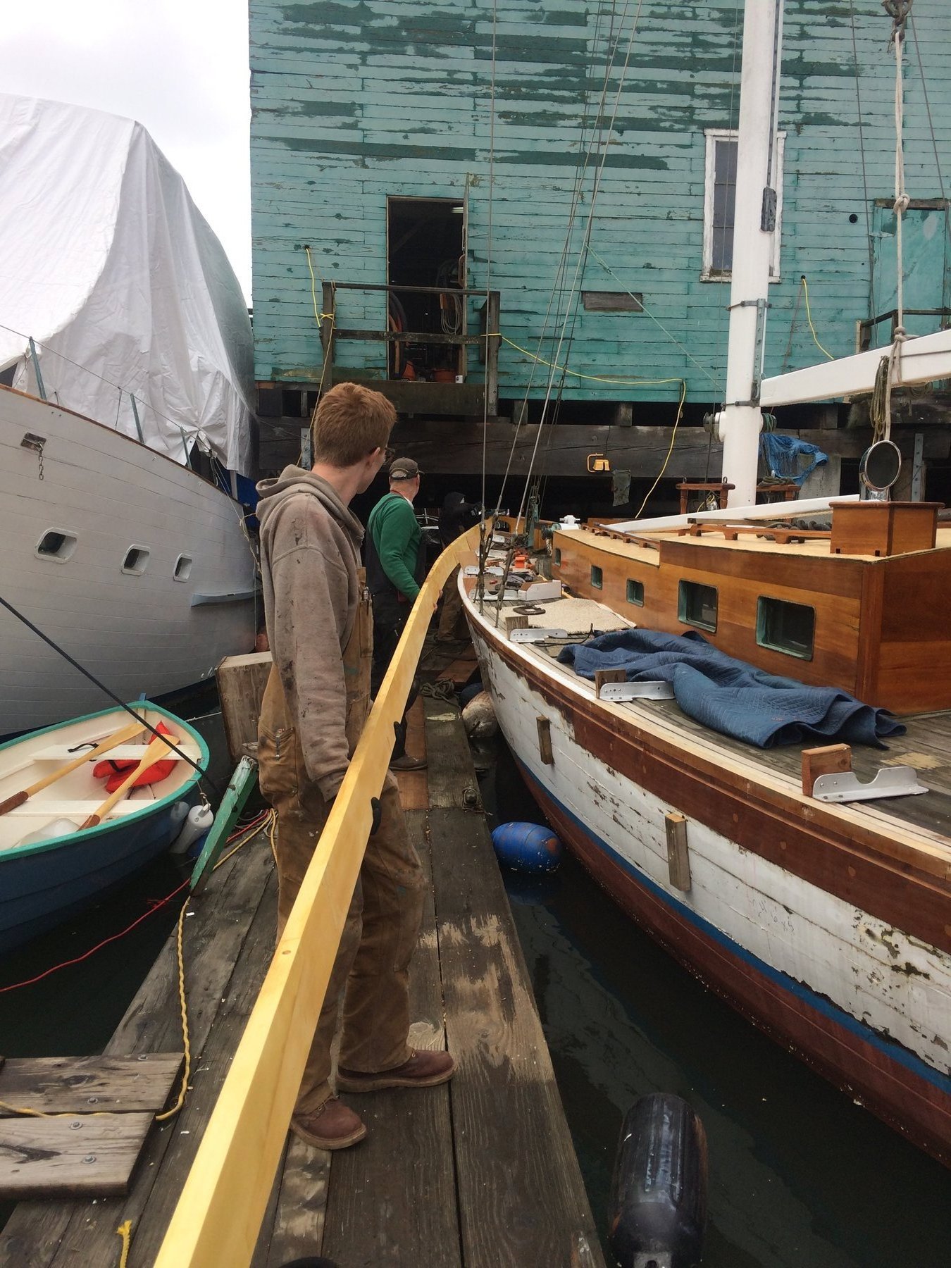A crew member tends lines aboard the classic 1946 Philip Rhodes-designed Merry Maiden, her wooden hull and traditional brightwork evident as she rests at the dock in Washington's Puget Sound.