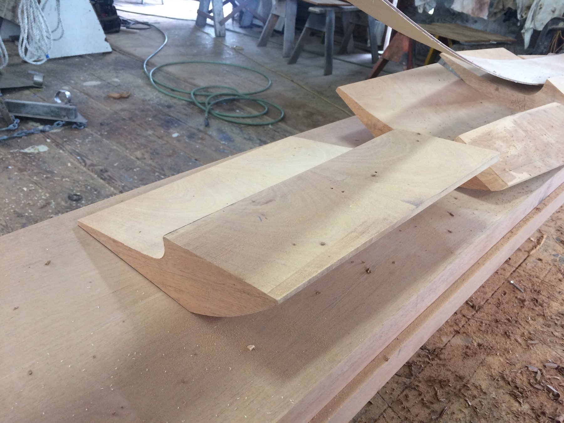 Freshly shaped wooden components take form in the boatyard as skilled craftspeople restore the classic lines of Merry Maiden, a 1946 Philip Rhodes design, with meticulous attention to traditional wooden boat construction.