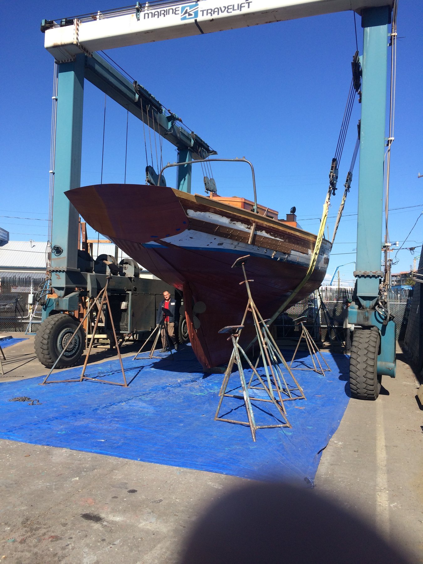 The classic 1946 Philip Rhodes-designed Merry Maiden sits on the hard in brilliant sunshine, her burgundy hull and traditional rigging showcasing the timeless elegance of mid-century yacht design in the Pacific Northwest.
