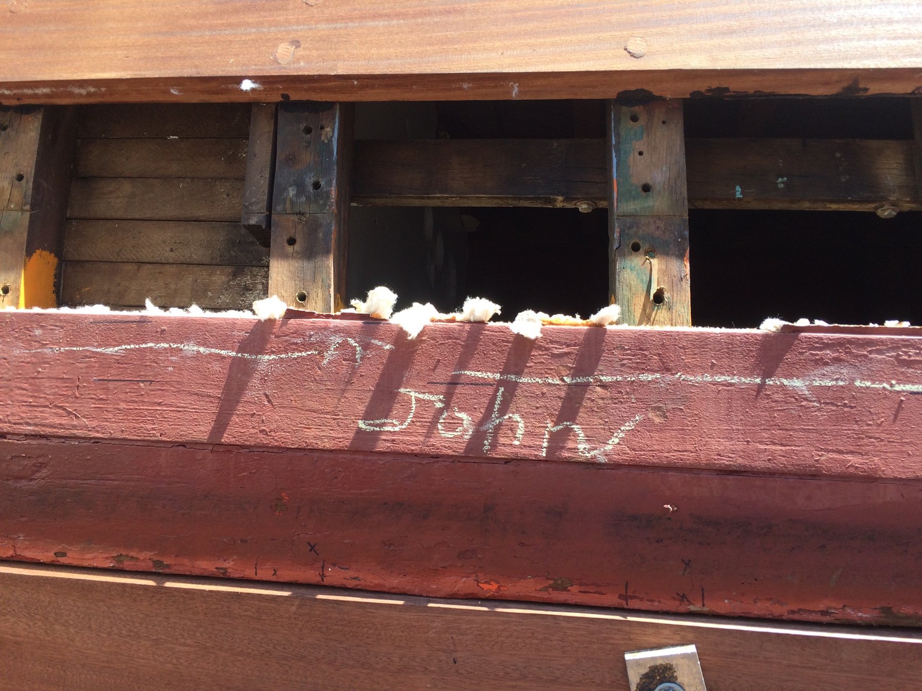Weathered hull and open cargo ports of the classic 1946 Merry Maiden reveal the vintage wooden construction and working character of this Philip Rhodes-designed yacht, with cotton battens marking sections of the red-painted planking.
