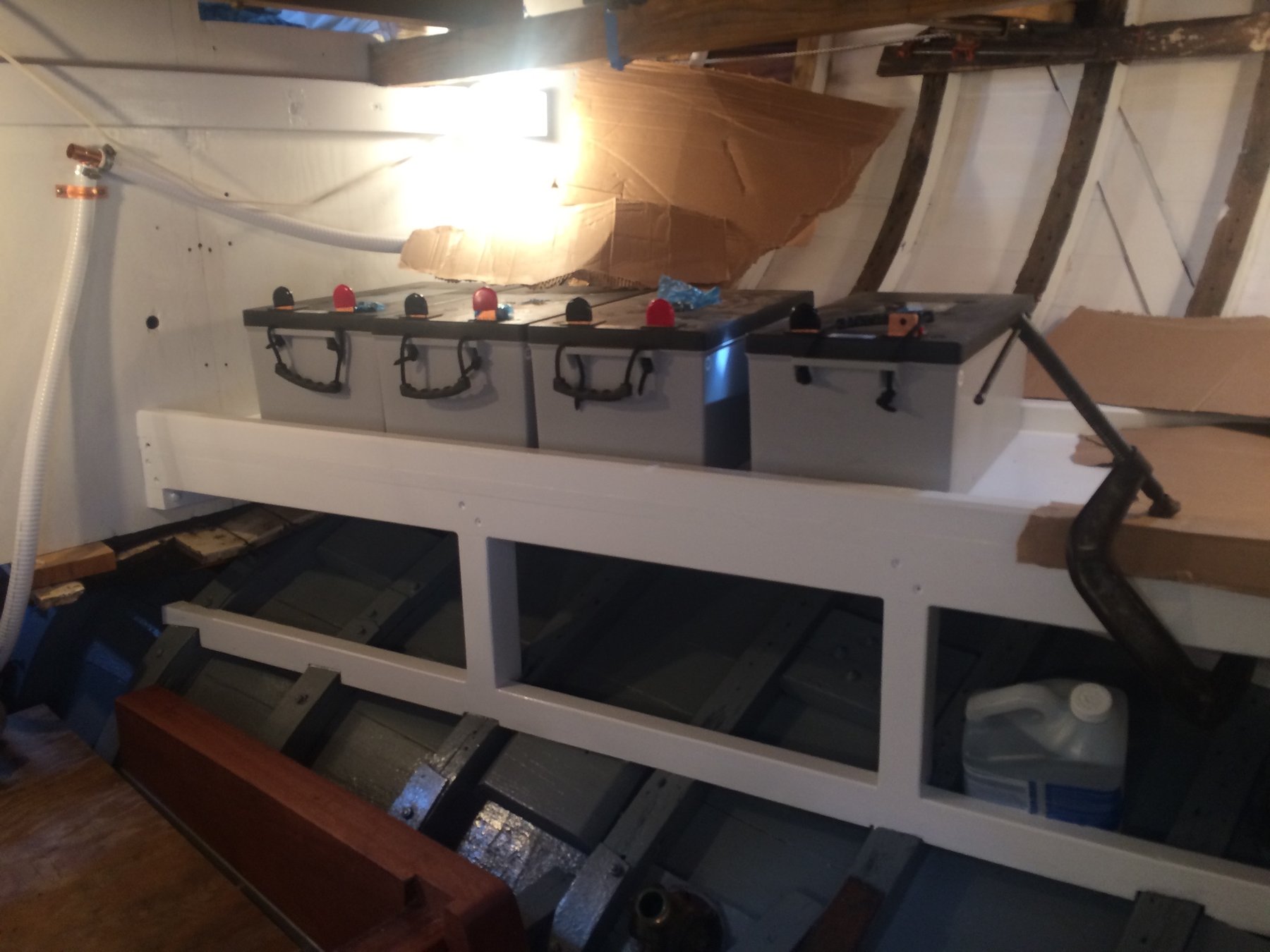 Below deck on the classic 1946 Merry Maiden, organized storage bins and dark cabin spaces reveal the utilitarian beauty of a Philip Rhodes design, with natural light streaming through hatches illuminating the boat's intimate interior.