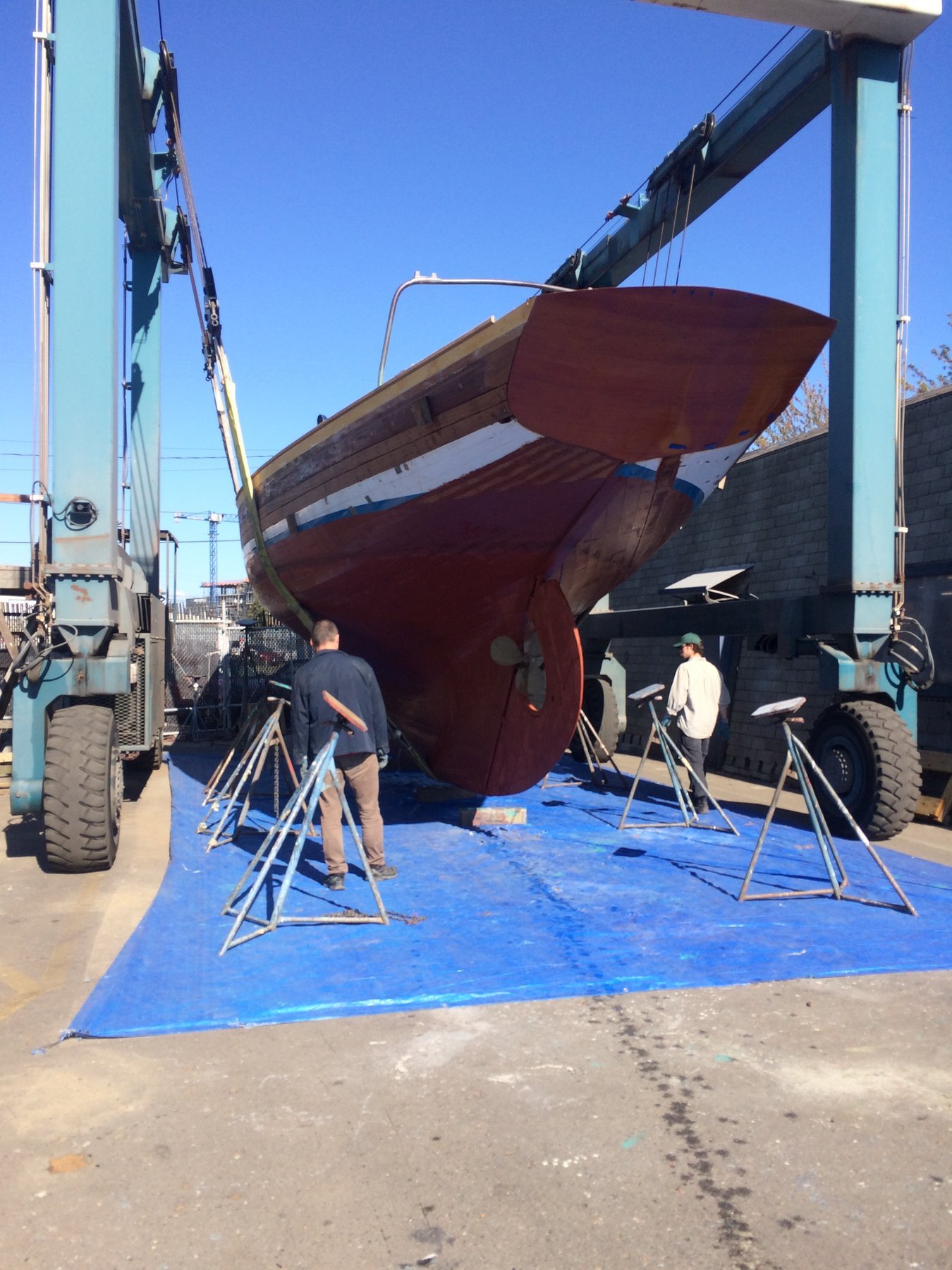 The classic 1946 Philip Rhodes-designed Merry Maiden rests at the dock under brilliant blue skies, her burgundy hull and traditional rigging a testament to timeless yacht design in the calm waters of Puget Sound.
