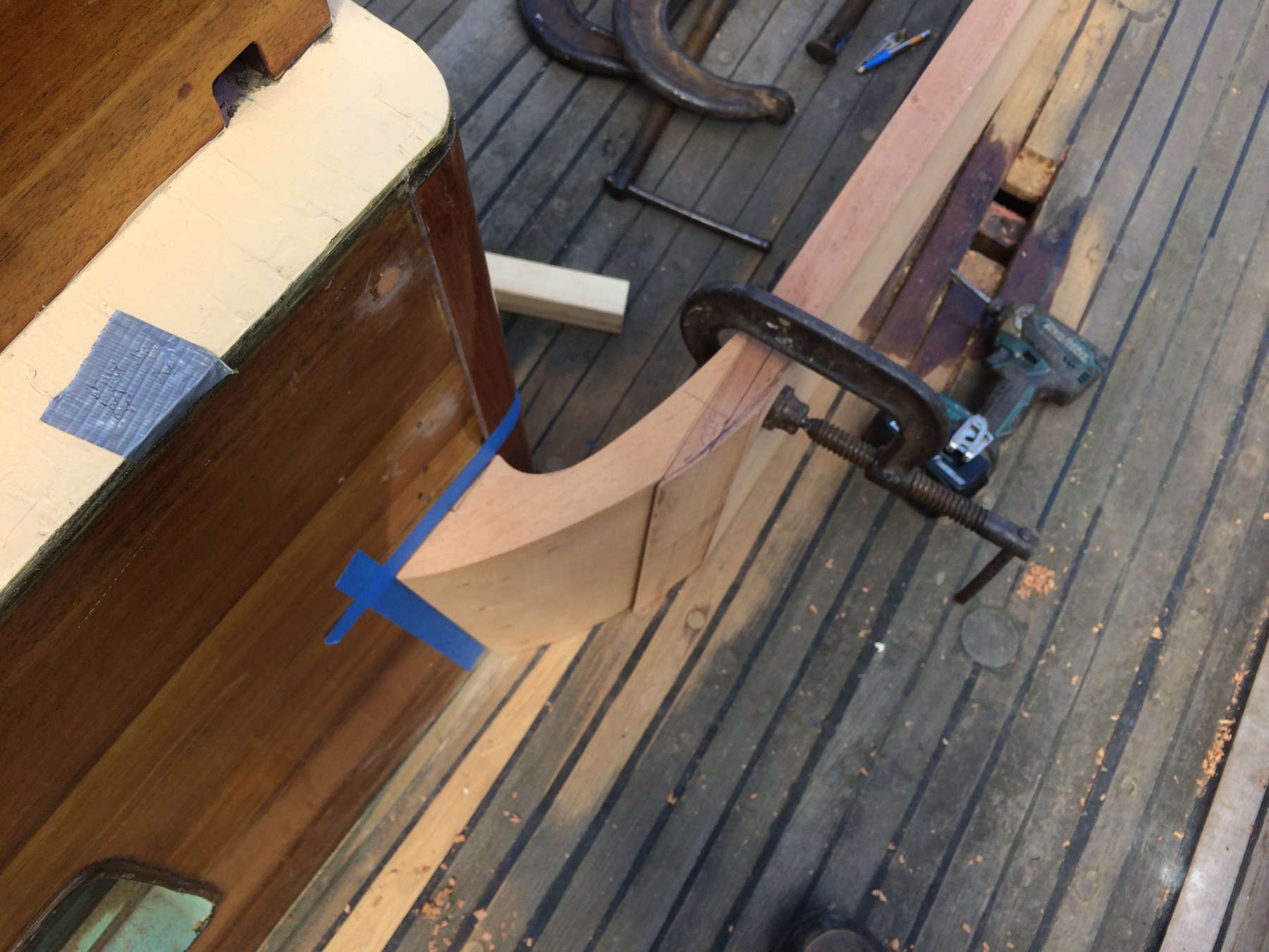 Overhead view of Merry Maiden's varnished teak deck and companionway, revealing the meticulous restoration work on this 1946 Philip Rhodes classic, with blue tape marking areas under repair in the Puget Sound boatyard.