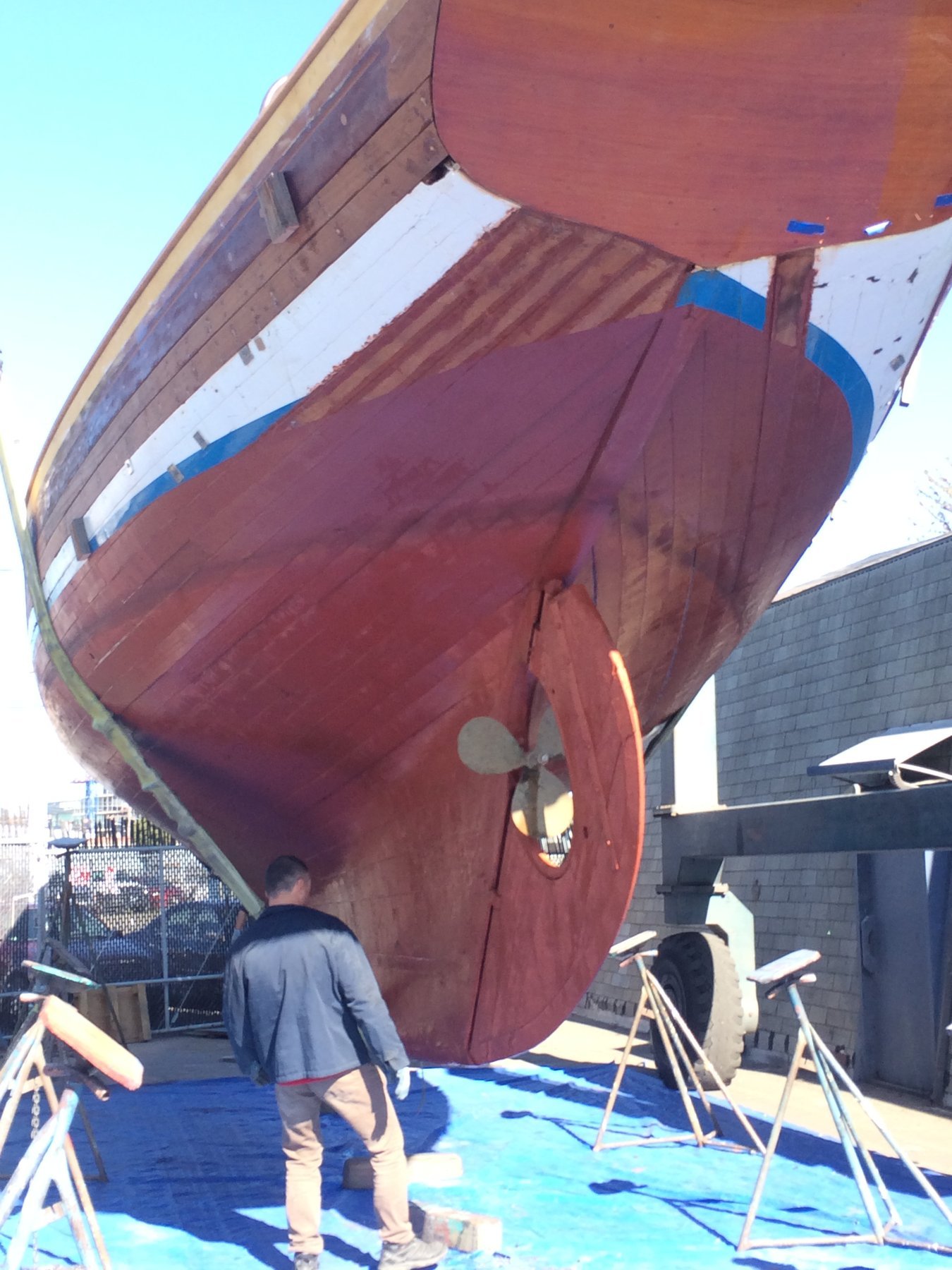 A crew member poses aboard the classic 1946 Philip Rhodes-designed Merry Maiden, her burgundy hull and white stripe gleaming in the Puget Sound sunshine.