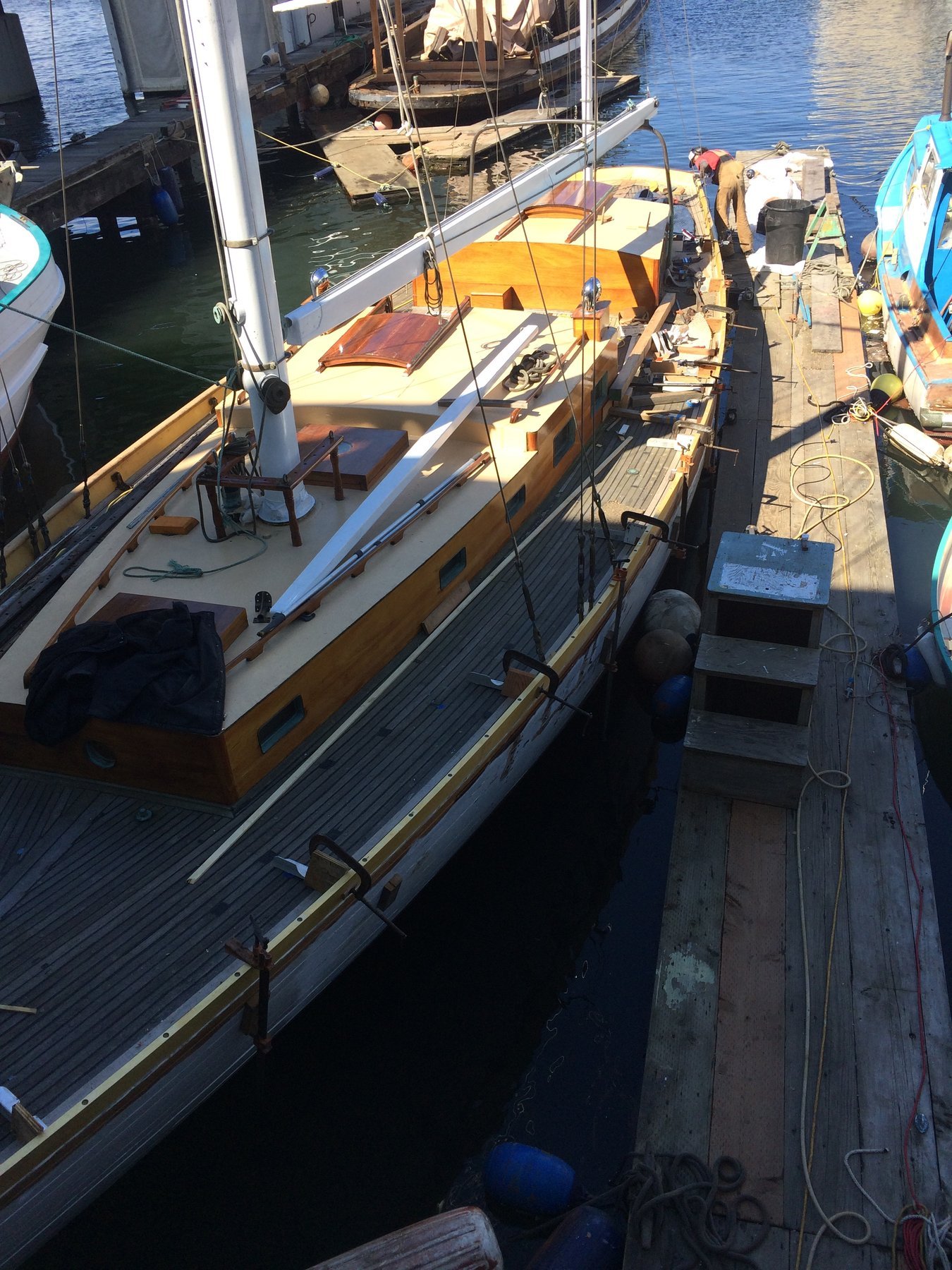 The classic 1946 Philip Rhodes-designed Merry Maiden rests peacefully at her Puget Sound mooring, her elegant white hull and traditional rigging bathed in golden afternoon light.