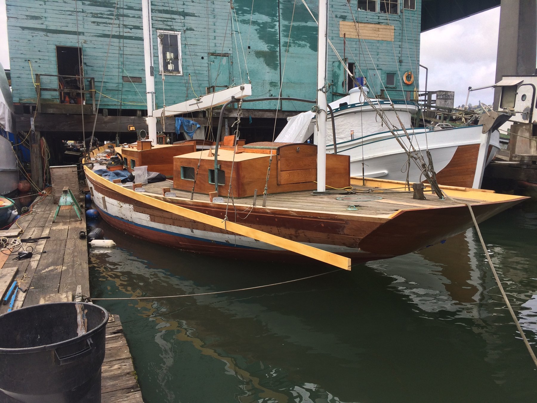 The classic 1946 Philip Rhodes-designed Merry Maiden rests peacefully at her Puget Sound mooring, her warm wooden hull and traditional rigging reflecting the quiet dignity of mid-century yacht design.