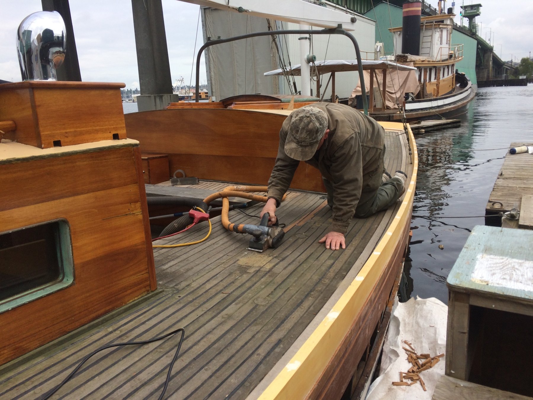 A craftsman carefully works on the deck of the classic 1946 Merry Maiden, attending to restoration details on this beautifully maintained Philip Rhodes-designed wooden yacht.