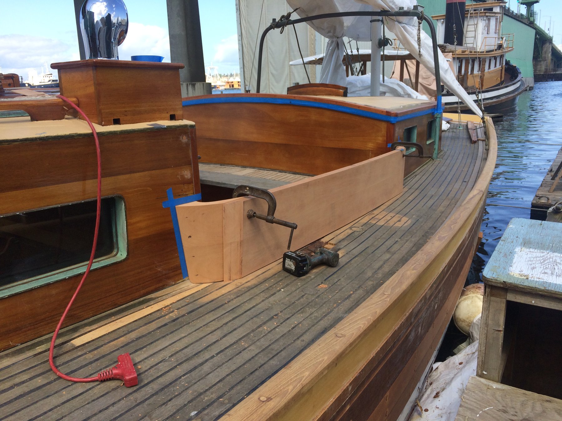 The teak deck and brightwork of the classic 1946 Philip Rhodes-designed Merry Maiden gleams in the spring sunshine while moored among fellow wooden vessels in Puget Sound, her graceful lines and meticulous restoration on full display.