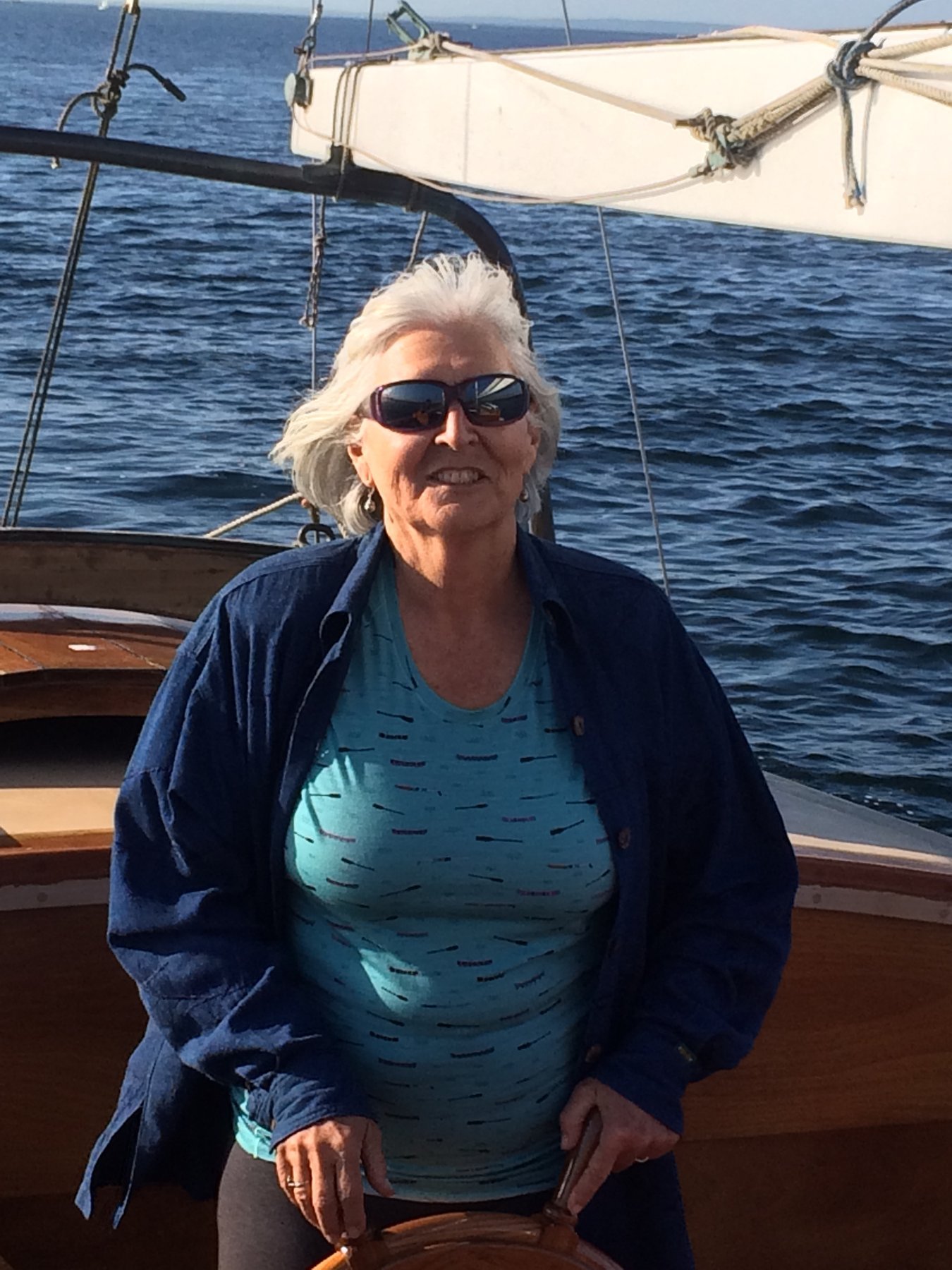 A captain enjoys a sunny afternoon aboard the classic 1946 Philip Rhodes-designed Merry Maiden, anchored in the sparkling waters of Puget Sound.