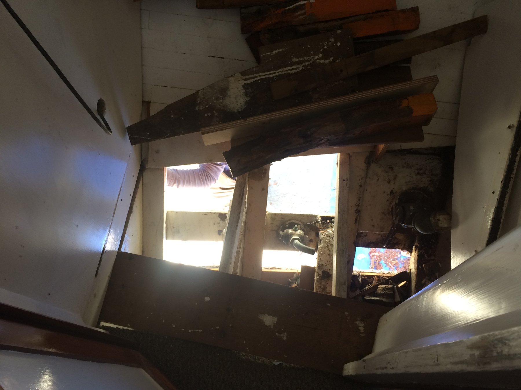 Sunlight floods through the companionway of the classic 1946 Merry Maiden, revealing the weathered wooden beams and structural details of this Philip Rhodes design undergoing restoration in the Pacific Northwest.