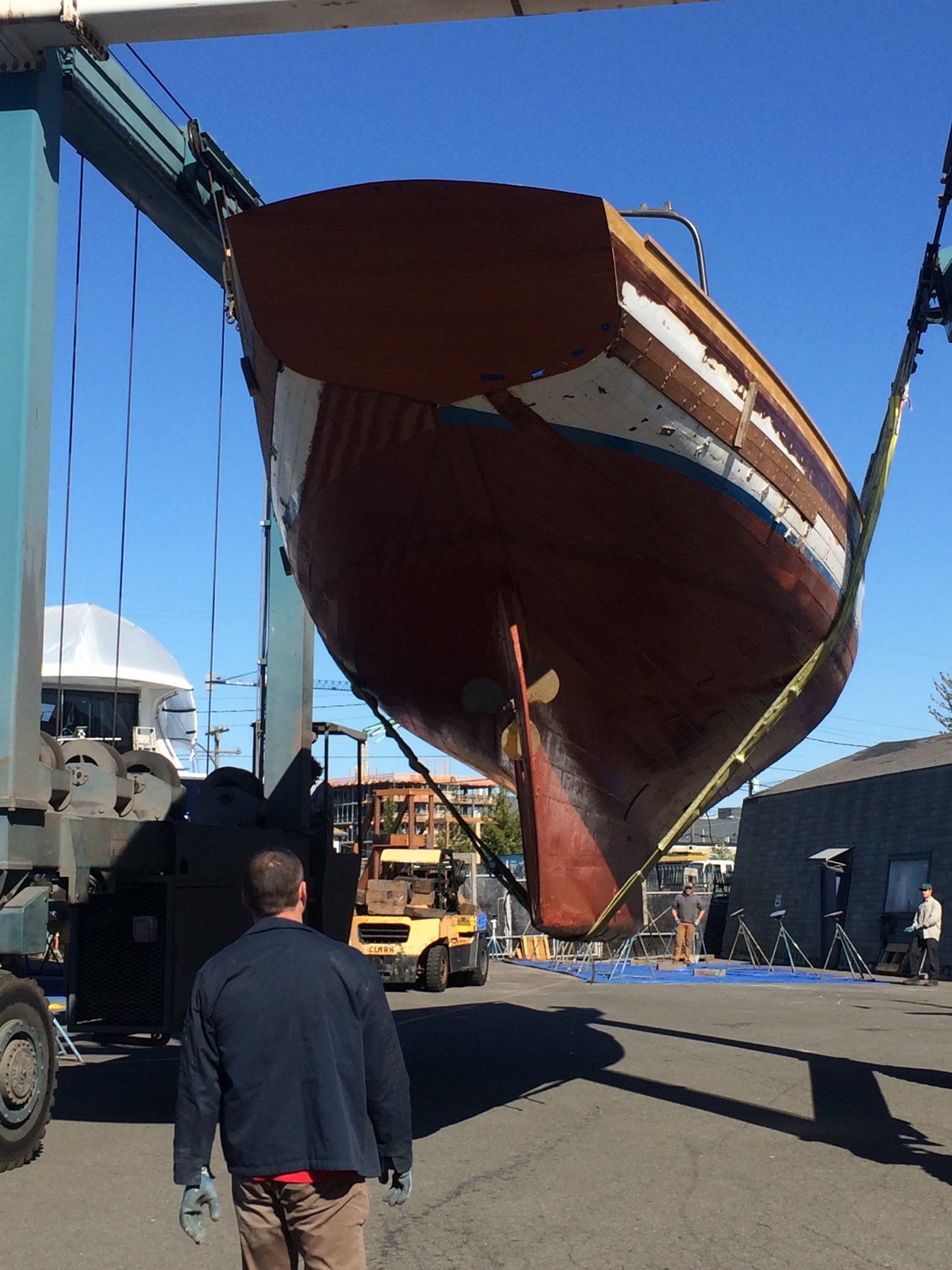 The Merry Maiden, a 1946 Philip Rhodes classic, suspended in the shipyard cradle for haul-out maintenance, her wooden hull exposed to the bright daylight for inspection and restoration work.