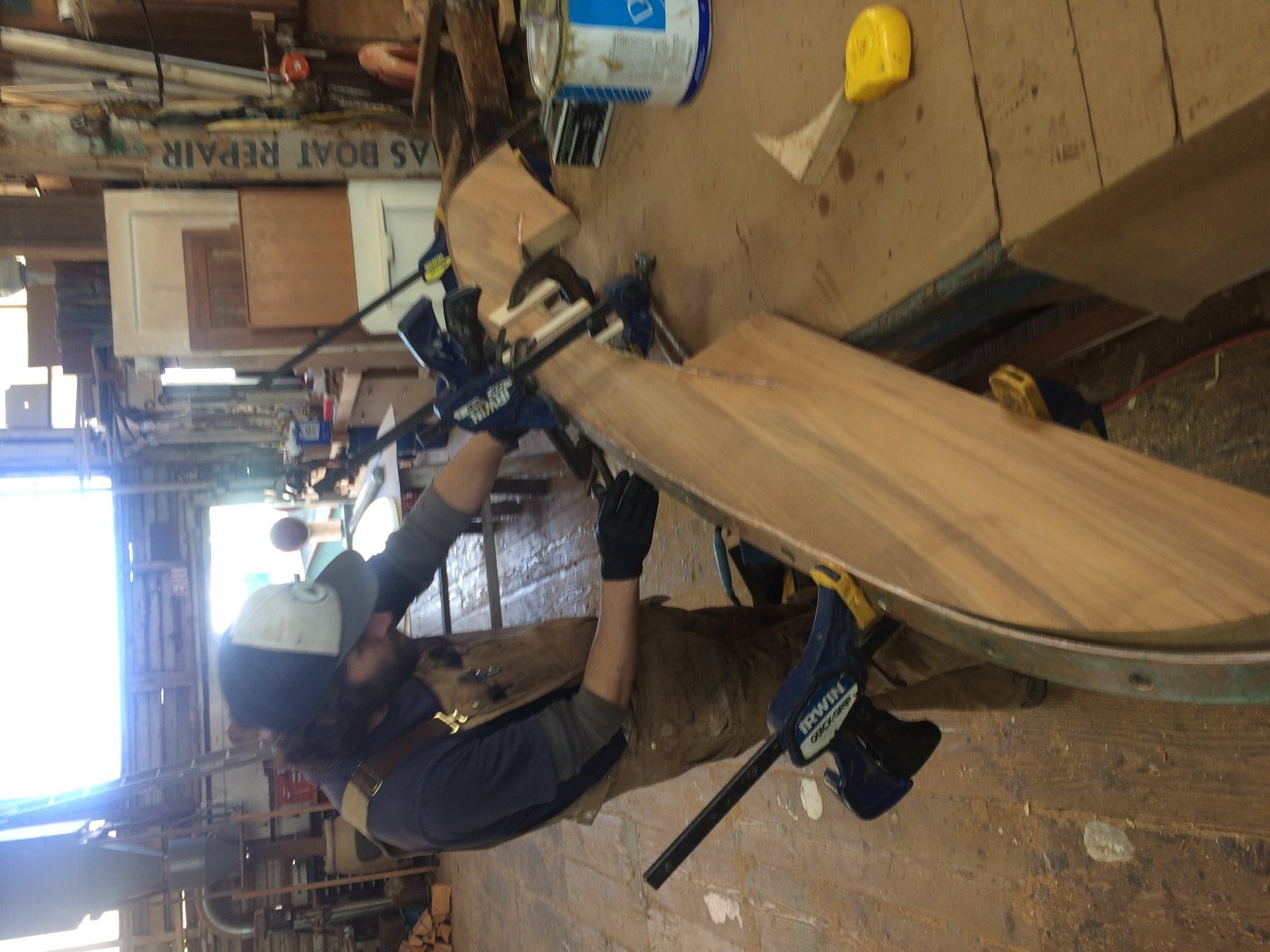 A craftsman works on the wooden hull of the classic 1946 Philip Rhodes-designed Merry Maiden, carefully shaping and fitting timber in this Puget Sound boatyard.